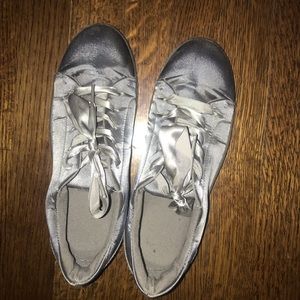 Silver satiny sneakers with ribbon laces.